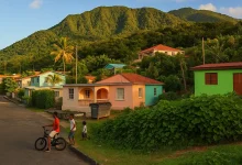 View of a vibrant a Dominica village with colorful houses and lush green mountains in the background, featuring three boys near a bicycle on a quiet street.