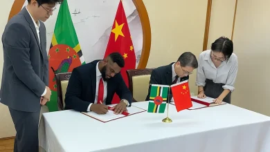 Hon. Cassanni Laville and Chinese Ambassador to Dominica Chu Maoming sign documents at the official signing ceremony