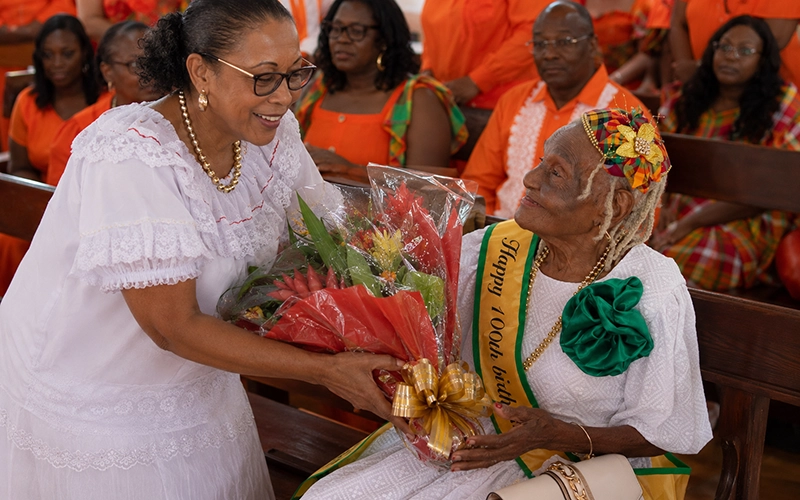 Sylvanie Burton presents a bouquet to a 100-year-old birthday Lucille Pascal, during a church celebration in Grand fond