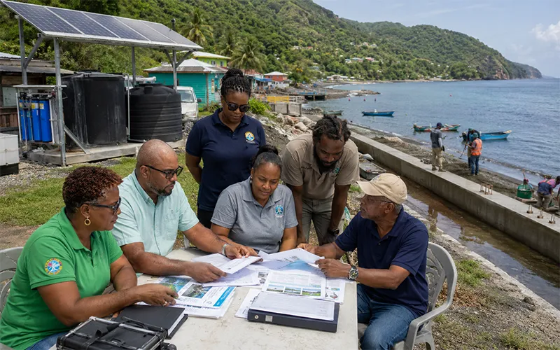 Dominican climate planners and community representatives reviewing resilience, marine protection, and sustainable energy project plans in a coastal setting.