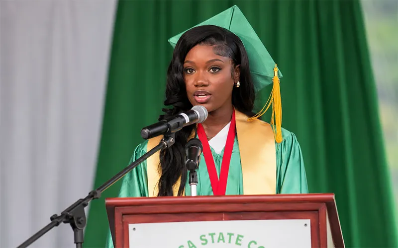 Close-up of Dominica State College Honours Ayhesha Charles as 2026 Valedictorian speaking at the podium as valedictorian during the Dominica State College graduation ceremony.