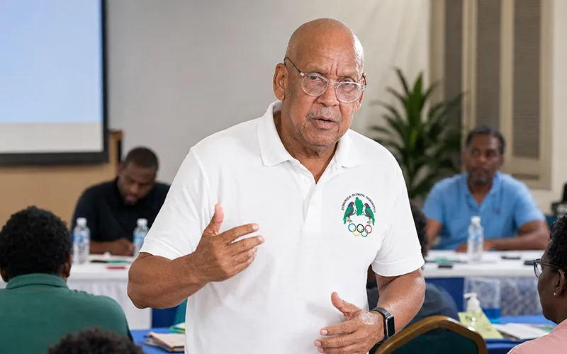 Billy Doctrove wearing a white Dominica Olympic Committee polo shirt while speaking at a sports training workshop in Dominica.
