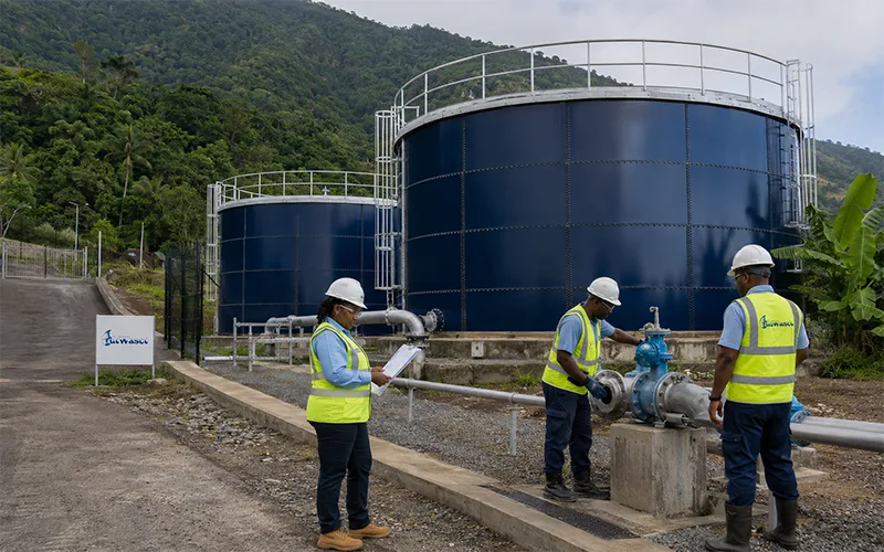 DOWASCO technical personnel inspect newly completed glass-fused-to-steel water storage tanks at a facility surrounded by Dominica’s mountainous vegetation.