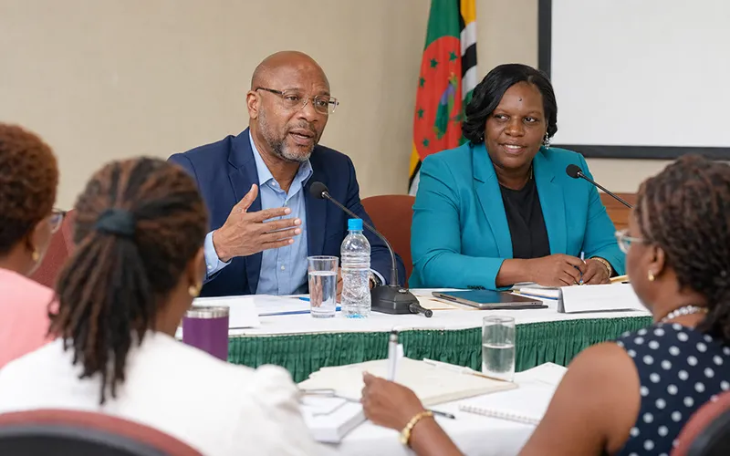 Mervin Alexander and Kathleen Cornelius seated together at a head table during a professional teachers’ session in Dominica, speaking with educators in the room.