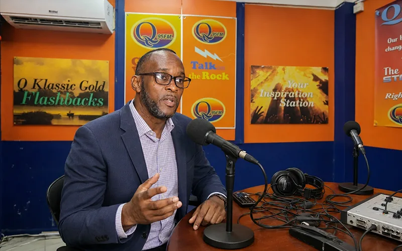 Simeon Joseph speaking seriously in a Dominica radio studio during an interview about political manifestos and campaign promises.